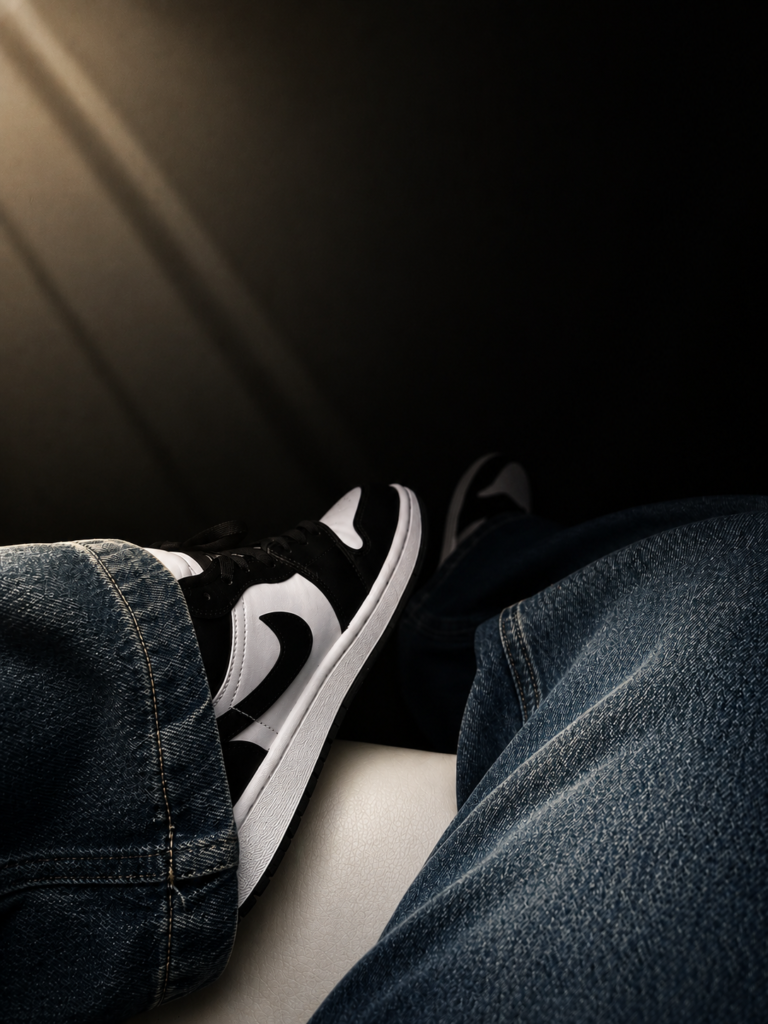 Stylish black and white sneakers with blue denim jeans in a cinematic low-light aesthetic, creating a modern streetwear fashion look.